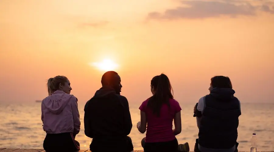 Four friends enjoy a sunset as an emblem of how to make sober friends