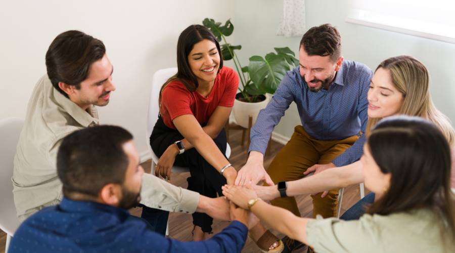 A group of recovery advocates in a circle with hands joined at center