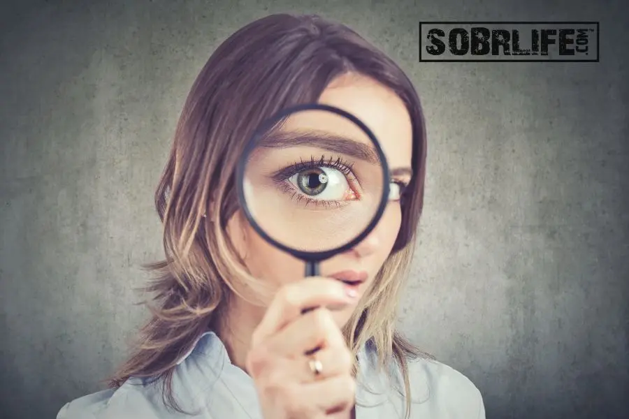 A woman with a magnifying glass shows the concept of relapse autopsies