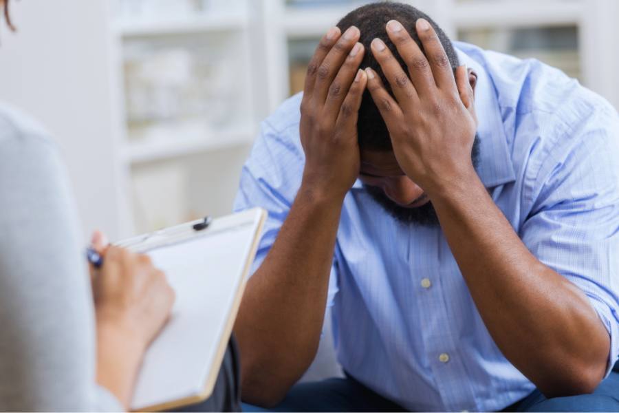A man with head in hands to show the concept of mental health crisis