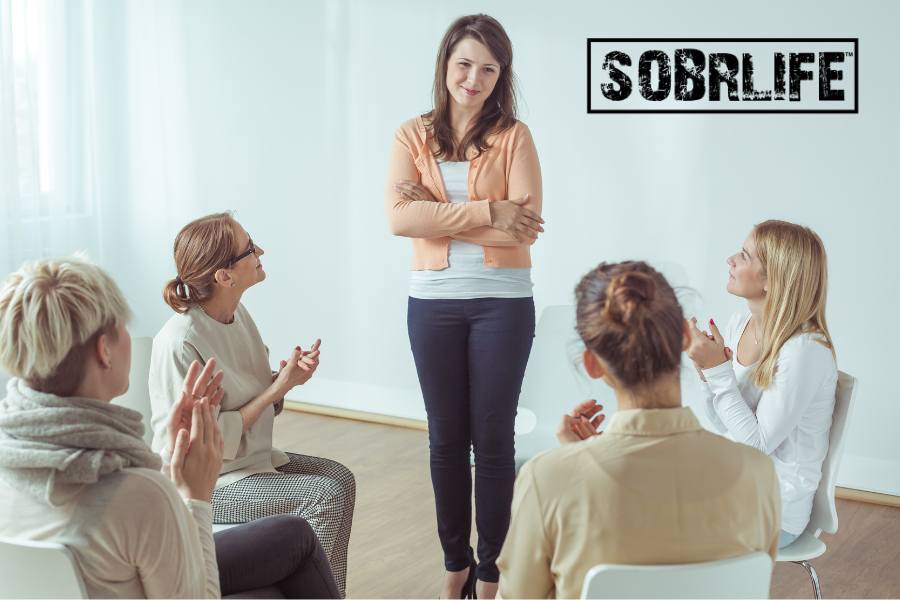 A peer recovery support meeting of women applauds the speaker sharing