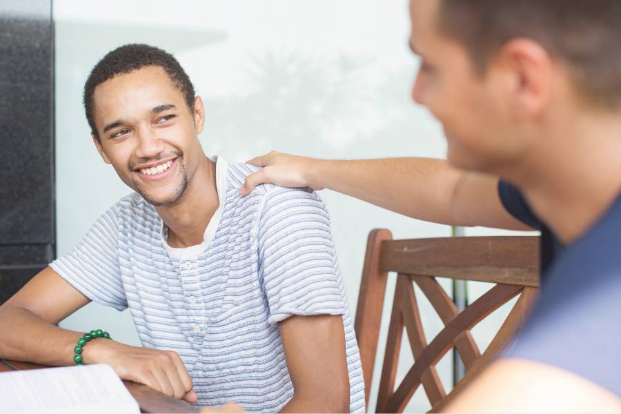 A man with his hand on the shoulder of another guy to show concept of sober support