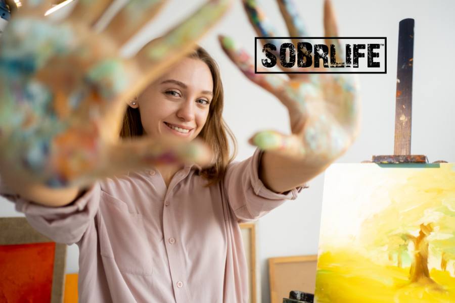 An artist shows her painted hands in a SOBRLIFE blog on art therapy for addiction recovery